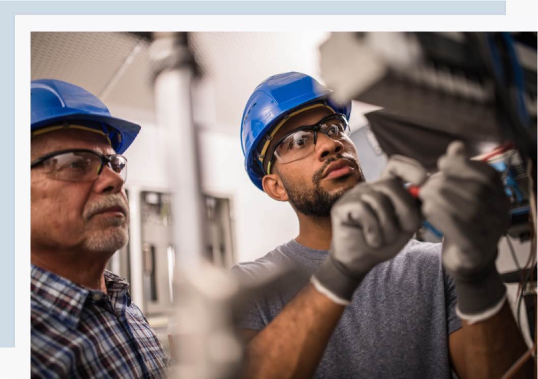 Mentorship program A man wearing a hard hat working with a mentor in the field engineering student at Rice's online MEML program.
