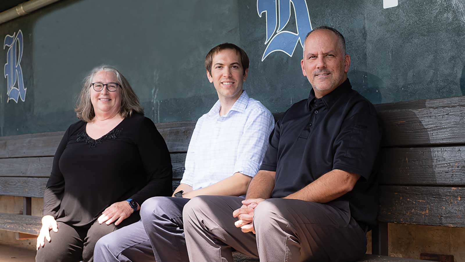 Statistics professors Kathy Ensor and Dan Kowal, and Clark Haptonstall, chair and a professor in the practice of sport management at Rice, sit in the dugout at Reckling Park, the university’s baseball field.