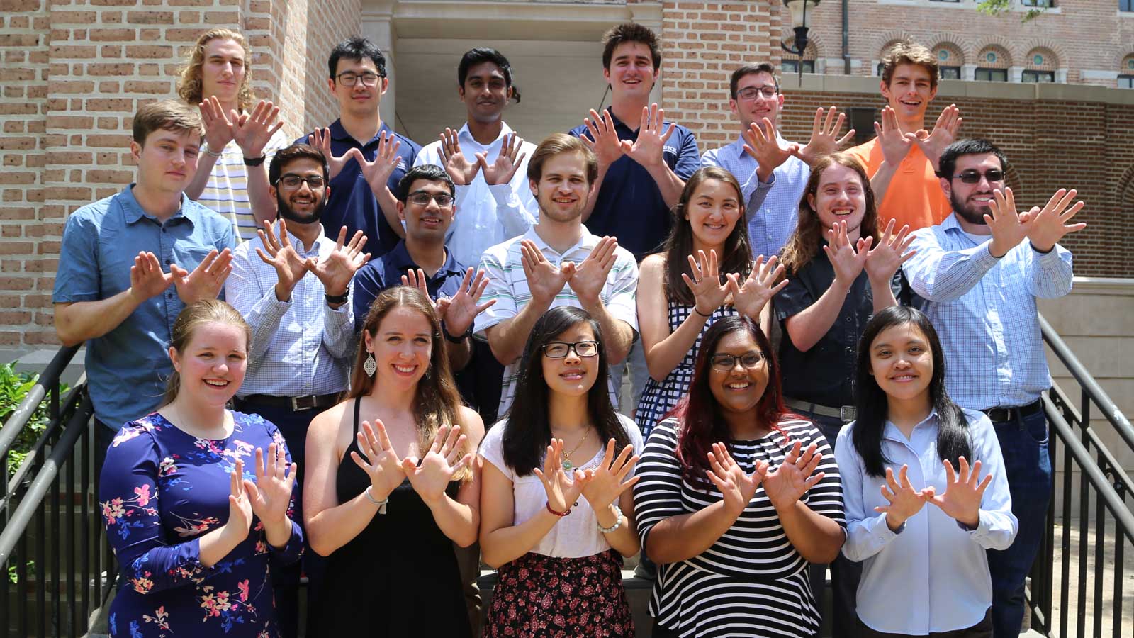 Rice students holding up owl hands