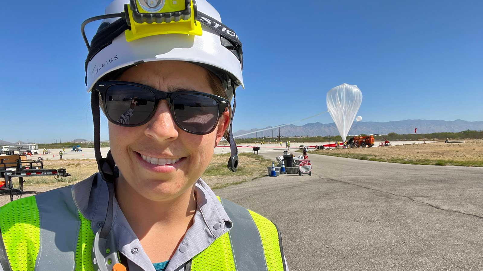 Jami Tullius wearing hard hat and sunglasses with space balloon in background.