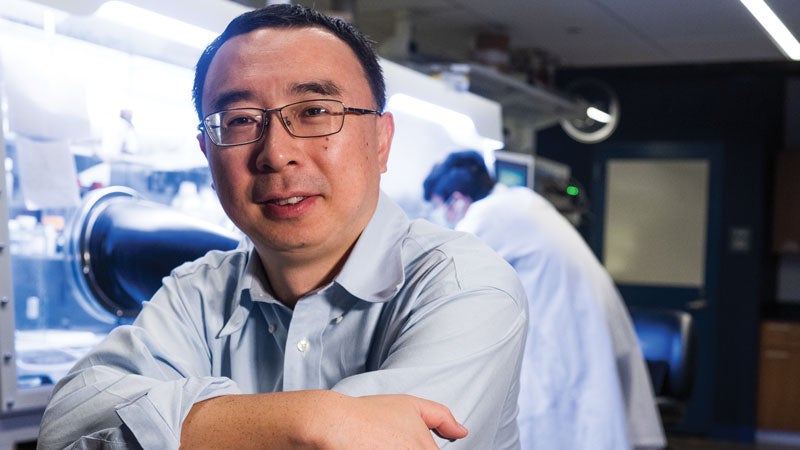 Ming Tang sitting with his arms crossed looking into camera