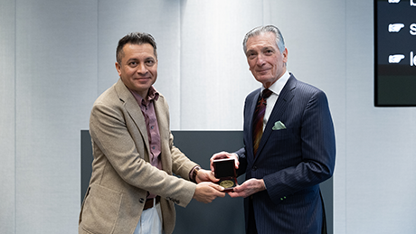 Aditya Mohite of Rice and Donald Sadoway of MIT stand together in front of a podium holding a medal in a gift box.