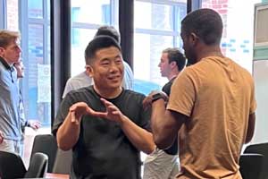 Two individuals speaking to one another inside a classroom