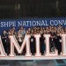 Society of Hispanic Professional Engineers members make Rice Owl hands behind a sign that reads "Familia"